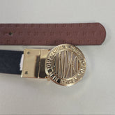 Gold belt buckle with engraved design on a gray background
